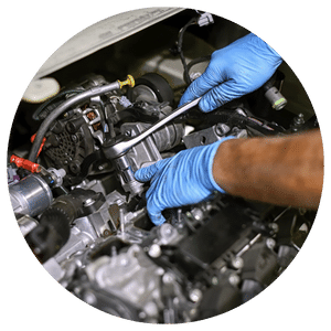 technician wearing blue gloves working on a car engine