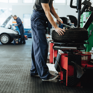 auto repair technician changing a tire on a wheel