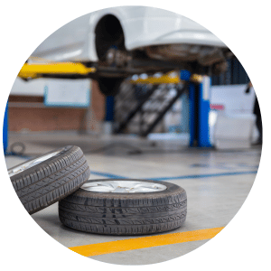 tires on the floor of shop with car on lift in the background