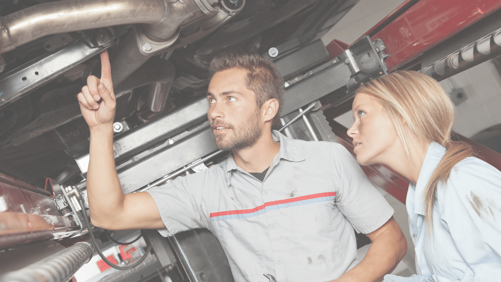 technician pointing to a car part underneath a car to another technician